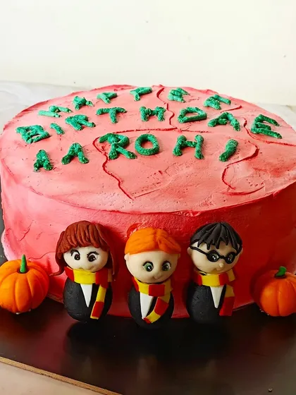 A cake inspired by Hagrid's "Happee Birthdae" cake for Harry Potter. This fun design features messy pink frosting and handcrafted figures of Harry, Ron, and Hermione.