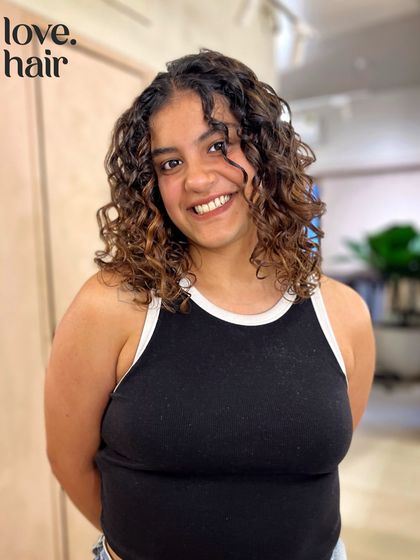 A happy client showing off her fresh cut and colour. The balayage brightens her complexion and makes her defined curls the star of the show.