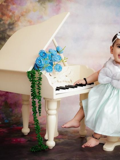 A mini maestro at her piano. This whimsical setup with a tiny grand piano and floral accents is perfect for capturing your baby's playful side.
