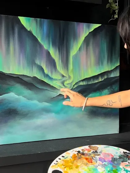 A little glimpse into my process. Here I am adding the final touches to this Northern Lights landscape painting, with my trusty palette full of dreamy colors right beside me.