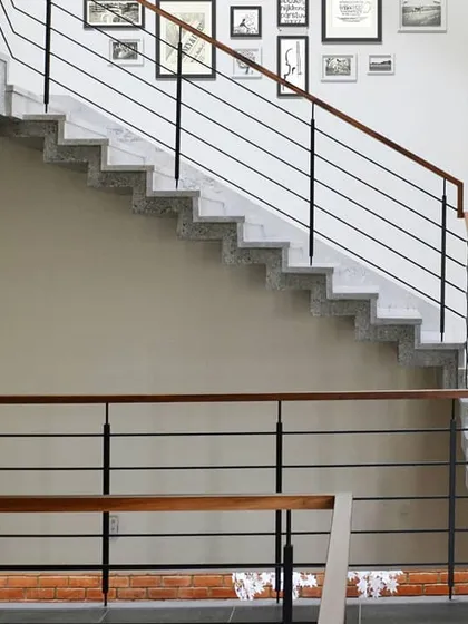 The polished concrete staircase is a key element of the home's modern aesthetic. The simple metal railing with a wooden handrail adds a clean, graphic quality.