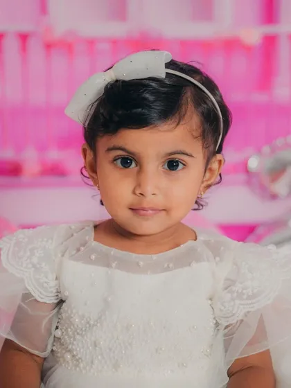 A simple, beautiful headshot against the soft pink background, highlighting her sweet face and pretty white bow.