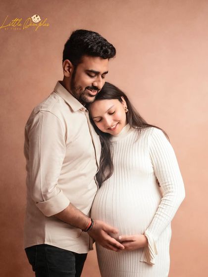 Simplicity and elegance define this studio maternity portrait. The couple's neutral-toned outfits and the tender pose create a timeless and classic look.