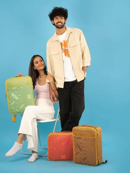 This studio shot for a luggage brand uses a clean, solid background to make the models and products stand out. The composition is balanced and showcases the bags in a stylish, aspirational context.