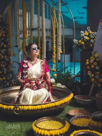 A unique Haldi setup, with the bride looking cool in sunglasses while seated in a large decorative urli bowl. I always look for creative ways to photograph traditional ceremonies.
