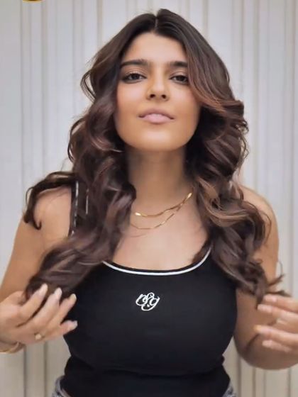 A model showing off her gorgeous, wavy brown hair with subtle highlights. The look is natural, healthy, and full of movement.