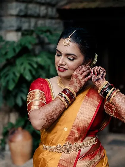 A close-up of a bride adjusting her earring, a beautiful getting-ready shot against the rustic stone wall of our courtyard.