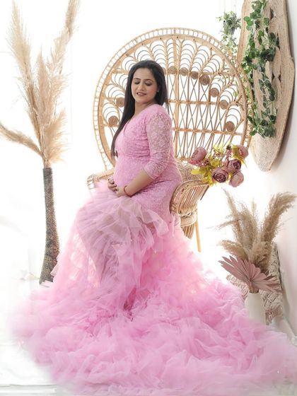 Blooming in pink. This elaborate ruffled gown creates a stunning visual, turning the mom-to-be into a beautiful flower herself, seated on a boho peacock chair.