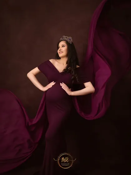 A confident and regal pose in a deep purple gown and crown. The flowing fabric adds a sense of drama and movement to this beautiful solo maternity shot.