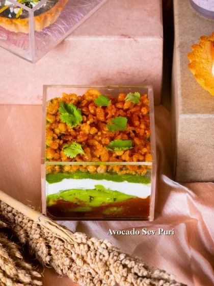 My deconstructed Avocado Sev Puri, layered beautifully in a clear container. It features layers of avocado, chutneys, yogurt, and crunchy sev, offering all the flavors of the classic chaat in a modern format.