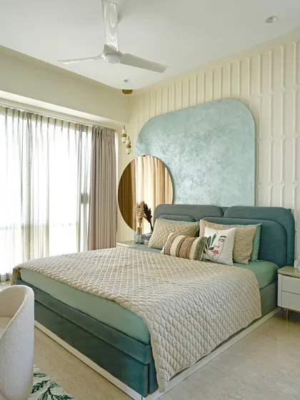 This serene master bedroom is a restful retreat anchored in a calming sage green palette. The design features a custom textured headboard and an MDF back wall, while a tinted mirror panel and fluted glass wardrobe add layers of understated luxury and functionality.