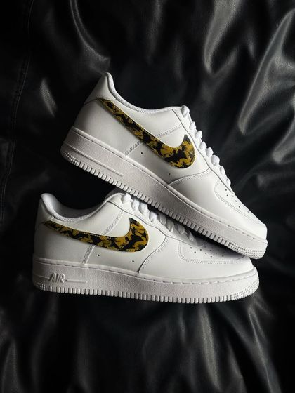 A pair of white Nike Air Force 1s with a classic leopard print pattern on the swoosh.