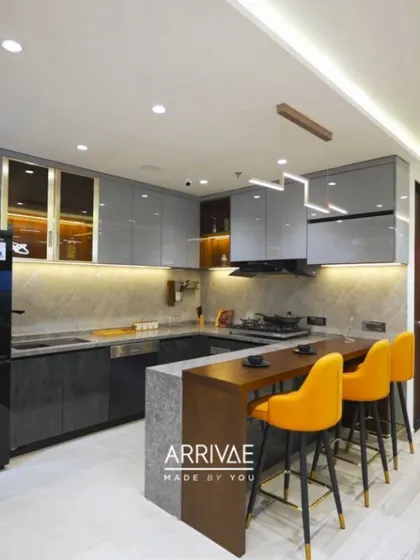 A stunning U-shaped modular kitchen featuring a sleek breakfast bar with vibrant yellow stools. This design combines glossy grey upper cabinets and dark textured lower units, all brought together with warm under-cabinet lighting and a modern pendant light, creating a perfect space for both cooking and socializing.