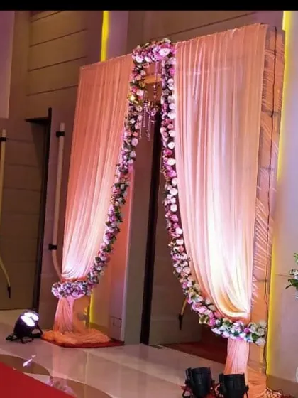 A simple yet elegant entrance decoration with peach-colored drapes and a floral garland. This is a great option for an indoor venue or banquet hall.