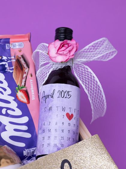 A personalized non-alcoholic wine bottle with a custom calendar label marking the wedding date. This is a unique and sweet way to count down to the special day.