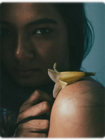 A macro close-up on the shoulder, with a small flower resting on the skin. This abstract and artistic shot focuses on texture, light, and the delicate interaction between the flower and the body.