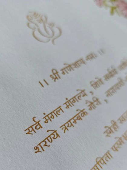 A close-up of the sacred Sanskrit verse on the Devanagari wedding invitation, written in beautiful gold ink.