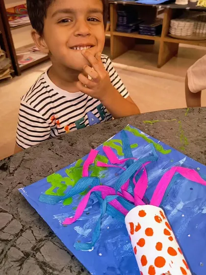 The cheeky smile says it all! This little boy is delighted with the colorful, dangly jellyfish he created.