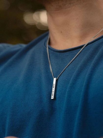 A man wearing a silver-toned stainless steel bar pendant. The simple chain and clean lines make this a popular and masculine choice for personalized men's jewelry.