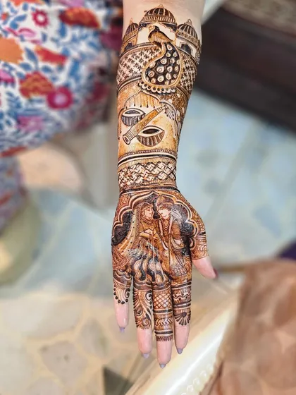 A full arm design telling a story. The palm features a couple portrait, while the arm includes scenes with musical instruments and a majestic peacock, all tied together with detailed patterns.