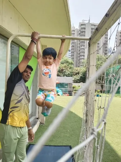 An instructor provides support as a young camper confidently hangs from the bars. Our summer programs are designed to help children build physical strength and self-assurance through guided, age-appropriate challenges.