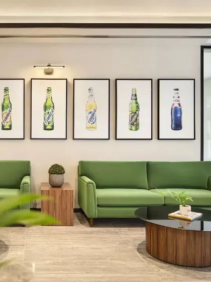 The waiting lounge for the Carlsberg office, where brand identity is expressed through color and art. The green sofas and framed bottle illustrations create a cohesive and memorable brand statement.