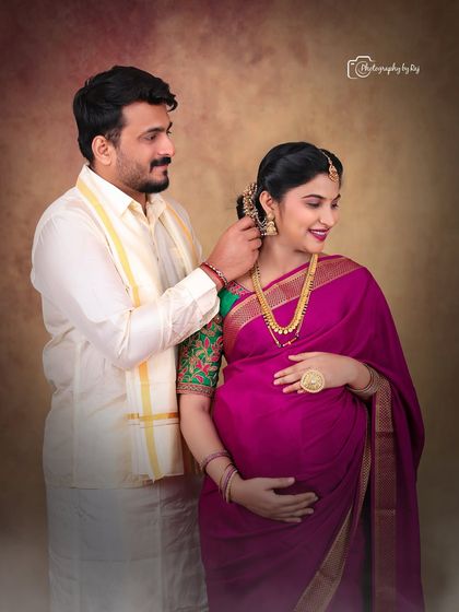 An intimate moment between a couple during their traditional indoor maternity shoot. The husband-to-be lovingly places a flower in his wife's hair.