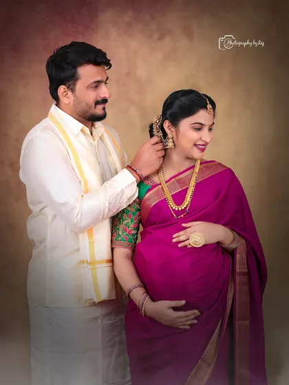 An intimate moment between a couple during their traditional indoor maternity shoot. The husband-to-be lovingly places a flower in his wife's hair.