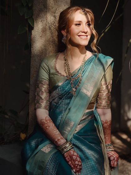 A smiling bride in the sunlight, her stained henna glowing warmly.