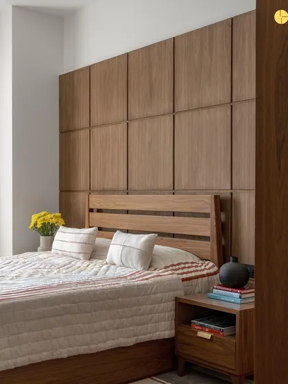 This bedroom features a clean, minimalist aesthetic with a focus on natural materials. The wood-paneled wall behind the bed adds warmth and texture, while the simple bedding and side table keep the space feeling uncluttered and peaceful.