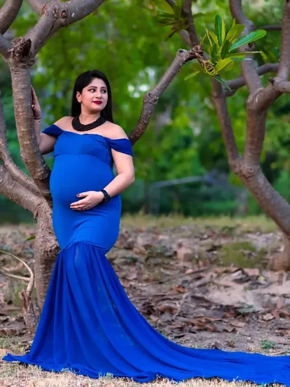 This royal blue gown with its long train creates a beautiful silhouette against the trees. It’s a perfect choice for a striking solo portrait during an outdoor pregnancy photoshoot.