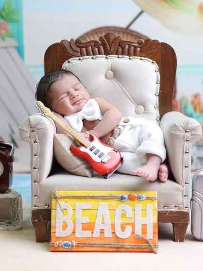 A different take on the beach theme, with the baby lounging in a mini armchair surrounded by travel props. This setup is perfect for a little globetrotter.