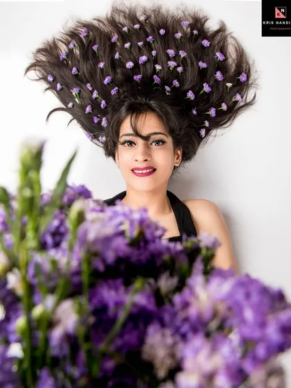 A creative studio portrait where small purple flowers are woven into the model's fanned-out hair. This is an example of how I love to play with unique concepts and props to create something truly artistic.