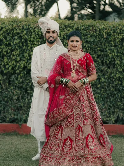 A regal portrait of the couple. The bride in her red lehenga and the groom in his white sherwani create a stunning and classic look.