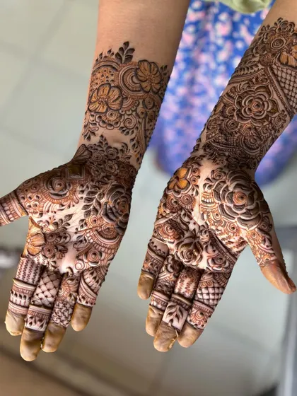 A beautiful, flowing design that combines different textures, from delicate flowers to shaded leaves and grid patterns. This is a great example of a full-coverage festive mehendi.