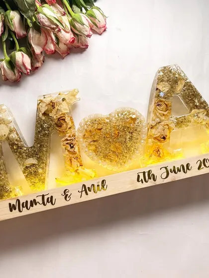 The same alphabet lamp, but with the lights turned on. The warm glow illuminates the preserved flowers, creating a magical effect.