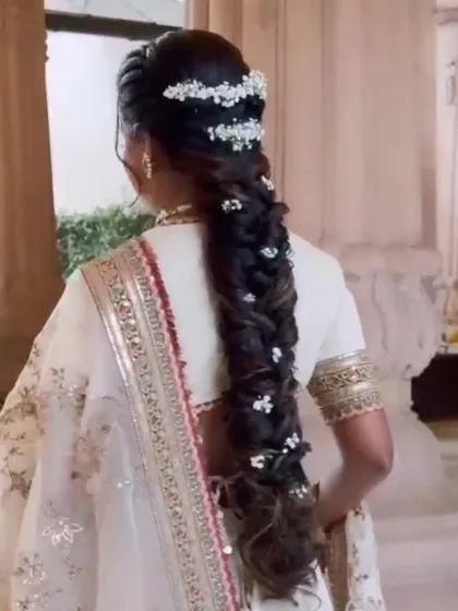 A soft, romantic messy braid interwoven with delicate baby's breath flowers. This textured fishtail braid is perfect for a daytime event or for a bride wanting a more bohemian and ethereal look.