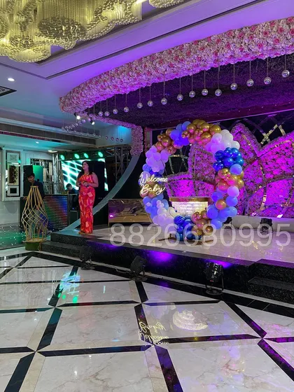This shows a large-scale 'Welcome Baby' decoration I set up on a stage in a banquet hall. The circular balloon arch in blue, white, and gold, complete with a neon sign, serves as a beautiful centerpiece for the event.