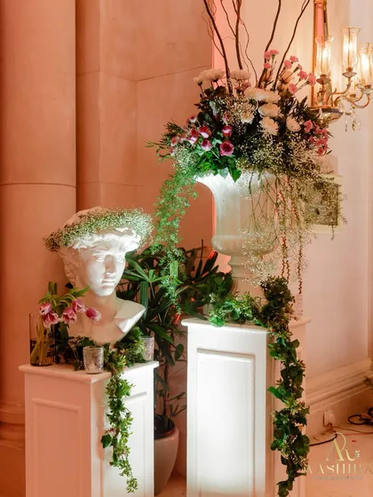 Art meets elegance in this detail shot, where a classical bust is adorned with a crown of baby's breath, surrounded by cascading greens and fresh blooms.