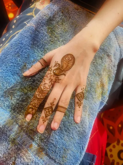 A festive mini design featuring a small peacock on the back of the hand. This is a quick and cute option for festivals like Teej or Karwa Chauth.