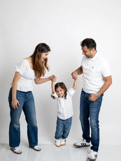 A playful family moment, with mom and dad swinging their happy son between them.