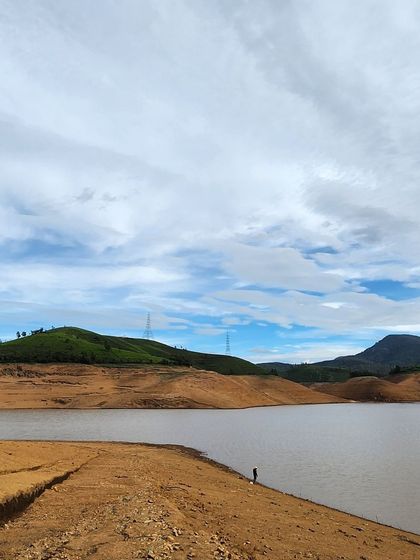 A serene lake reflecting the sky, with a lone figure enjoying the solitude. There's always time for personal reflection on our trips.