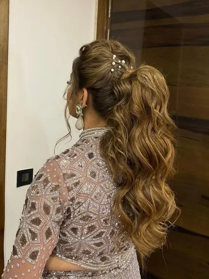 A messy, textured ponytail with pearl accessories. This is a soft and romantic take on the classic pony, perfect for an engagement or reception look.
