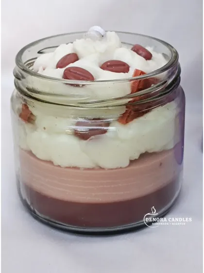 A layered coffee dessert candle in a mason jar, with whipped wax topping and coffee bean embeds.