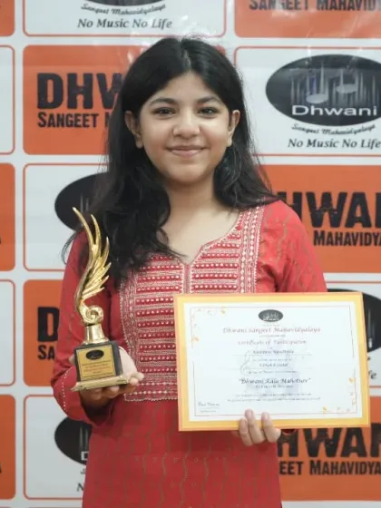 A student proudly holds her certificate and trophy.