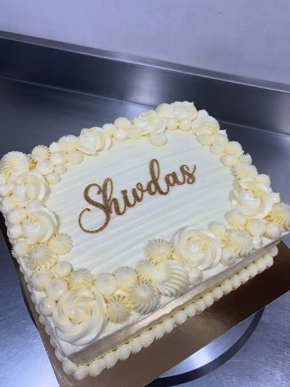 A classic Pineapple Gateau. This rectangular cake features elegant white-on-white piping and a beautiful custom name in gold. It's a timeless favorite.
