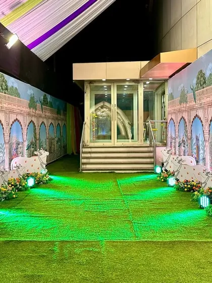 The entrance passage for the Bhagwat Sapta, designed to transport guests to Vrindavan. The walls are lined with printed panels showing palace arches and peacocks, while illuminated cow cutouts guide the way.