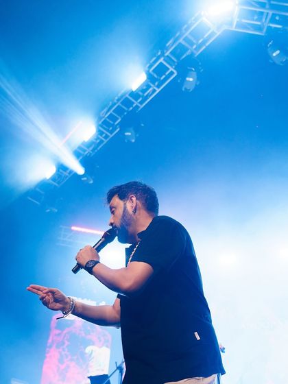 A singer captured mid-performance under dramatic blue stage lighting. I aim to freeze the energy and passion of live musical events.