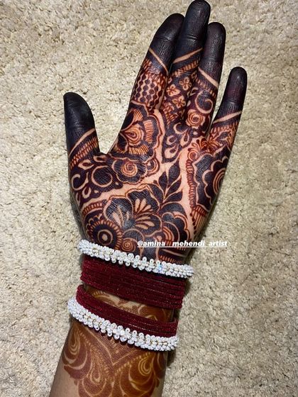 A lovely stained hand adorned with bangles, showing how beautiful a mature henna design looks with traditional accessories.