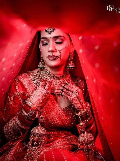 A powerful bridal portrait using a vibrant red veil to create a frame. The dramatic lighting and the bride's serene expression make this a truly artistic shot.